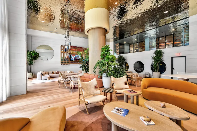 Double-height resident lounge with plants and soft seating