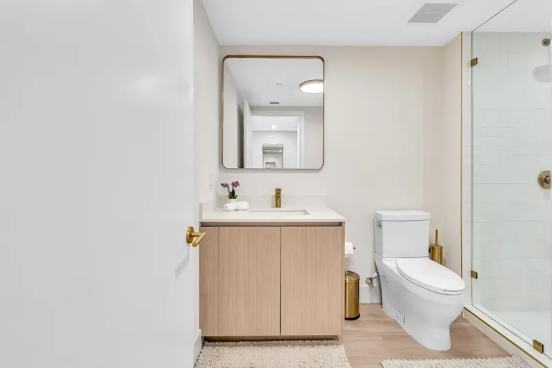 Bathroom vanity with oak cabinet, round-cornered mirror and gold fixtures